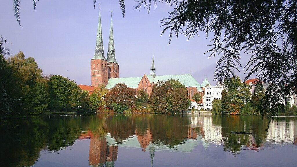 Blick über den Mühlenteich auf den Dom zu Lübeck. Der Dom spiegelt sich im Wasser.