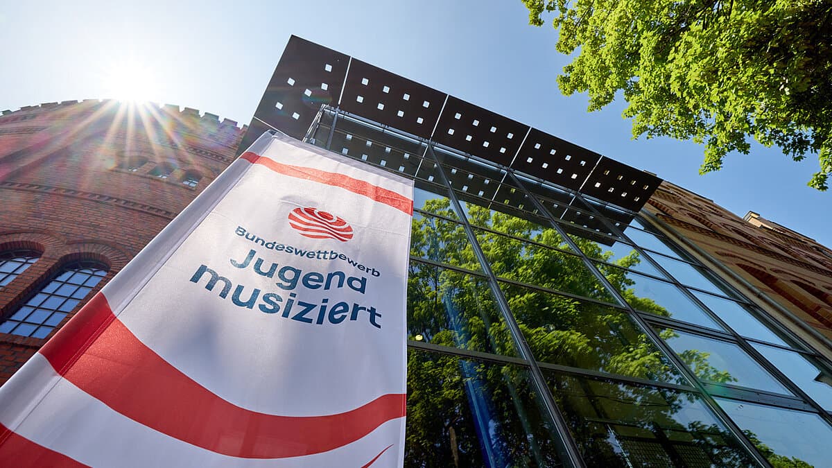 Jugend muisziert Fahne vor einer gläsernen Häuserfront