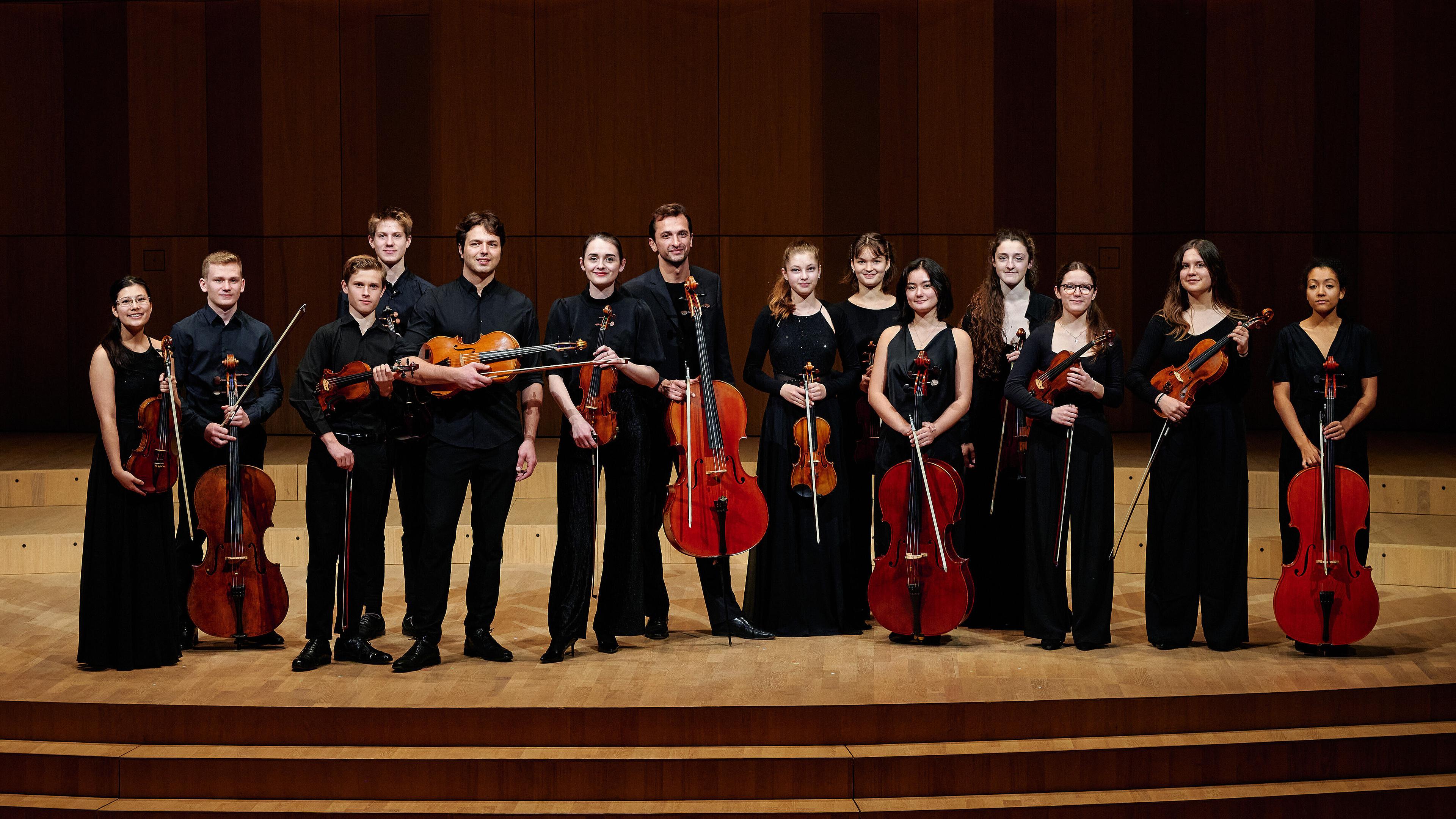 Die Musiker:innen des Konzerts posieren mit ihren Instrumenten auf der Bühne.