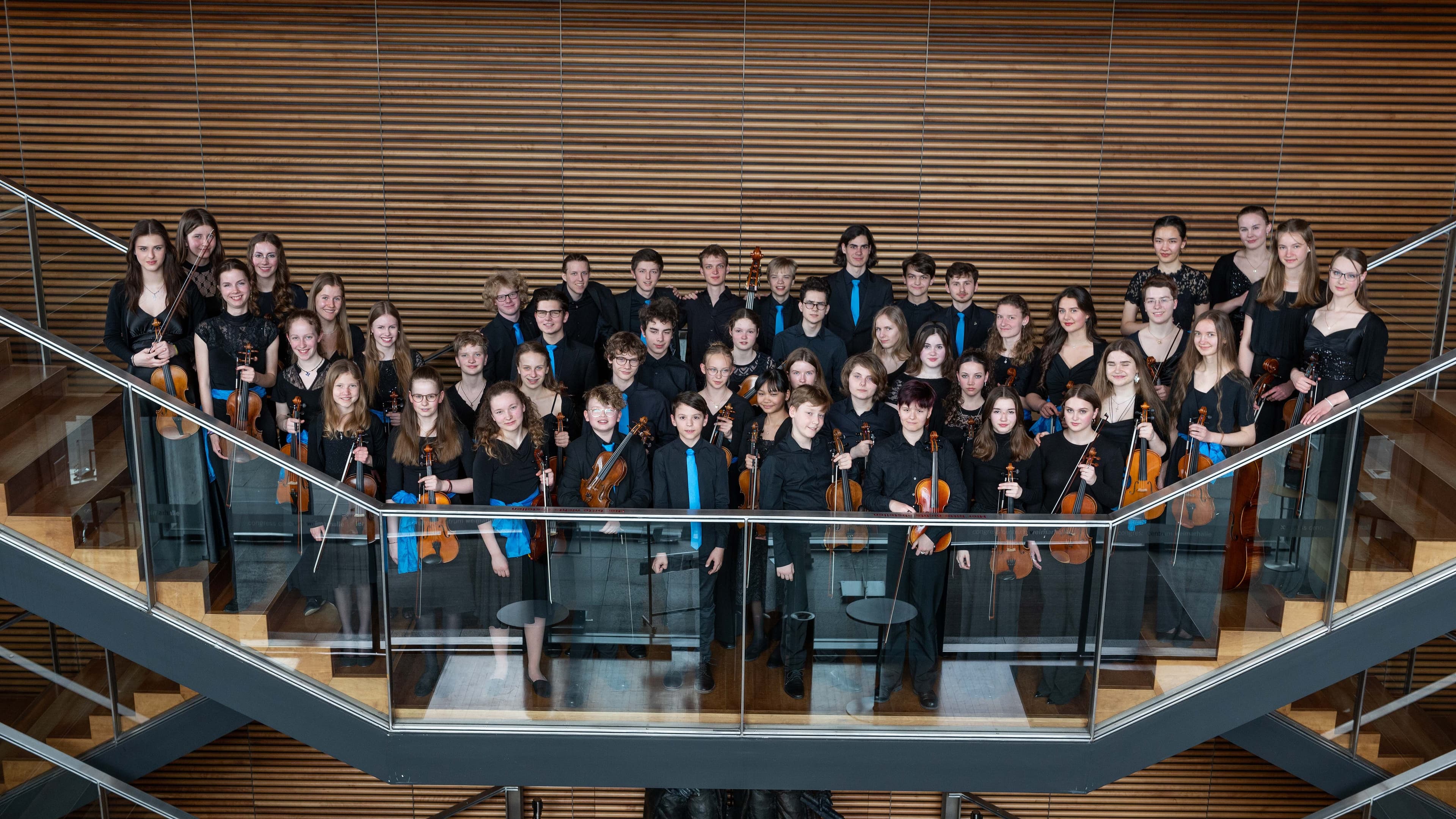 Die Orchestermitglieder posieren für das Gruppenbild in Konzertkleidung und mit Instrumenten in der Hand.